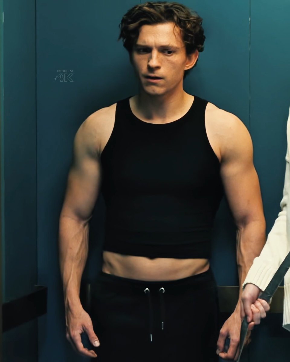 A muscular man with curly hair wearing a black tank top stands against a teal background, with a 'POP IN 4K' watermark visible.