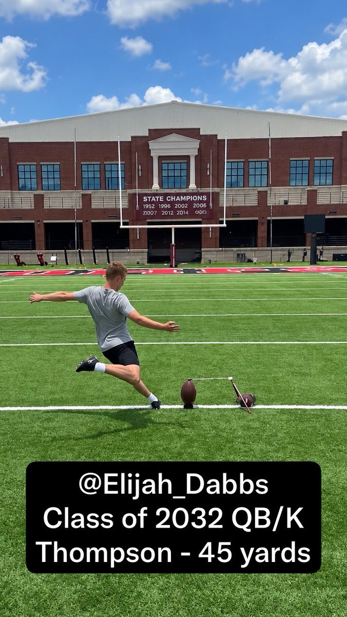 A young man kicking a football on a turf field in front of a stadium scoreboard listing 'STATE CHAMPIONS' years, with text '@Elijah_Dabbs Class of 2032 QB/K Thompson - 45 yards'.