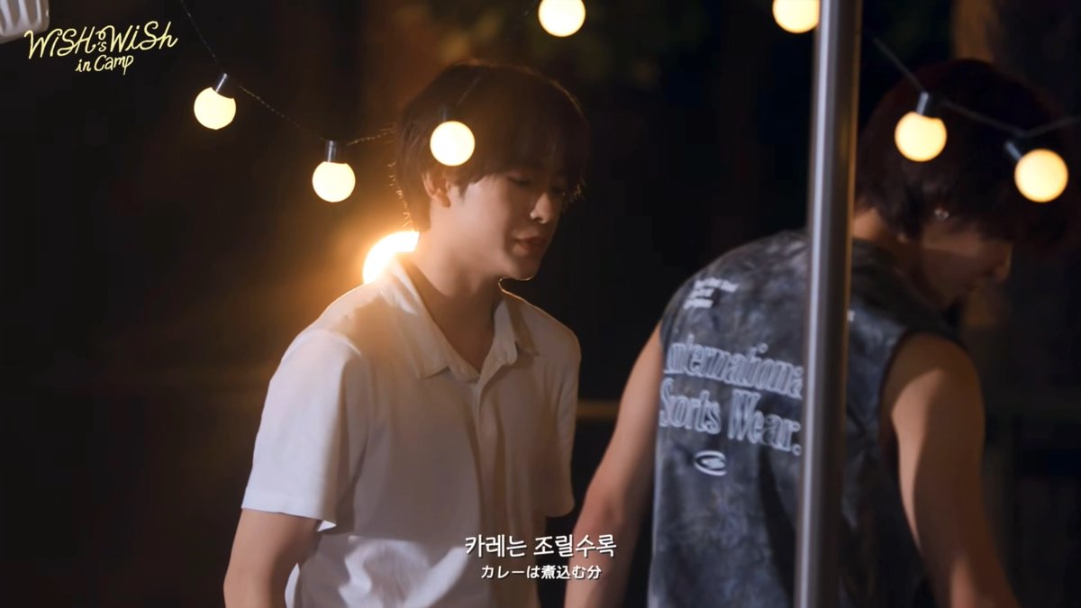 Two young men are shown at night with string lights overhead; one wears a white shirt and the other a gray sleeveless shirt with 'Supermadison Sports Wear' text, and the image contains the logo 'WISH ON WISH in Camp' along with Korean subtitles.