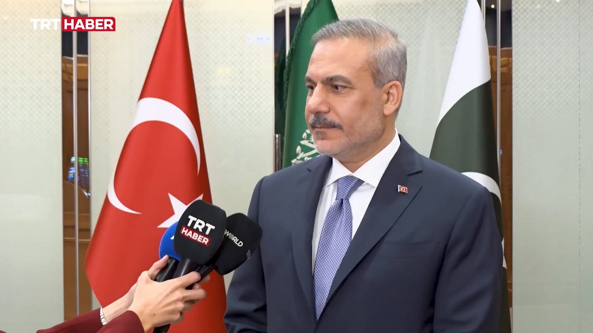 Turkish Foreign Minister Hakan Fidan speaks to TRT Haber and TRT World reporters in Riyadh, with the Turkish and Saudi flags visible behind him, following meetings under the Mecca Agreement regarding the Yemen issue.