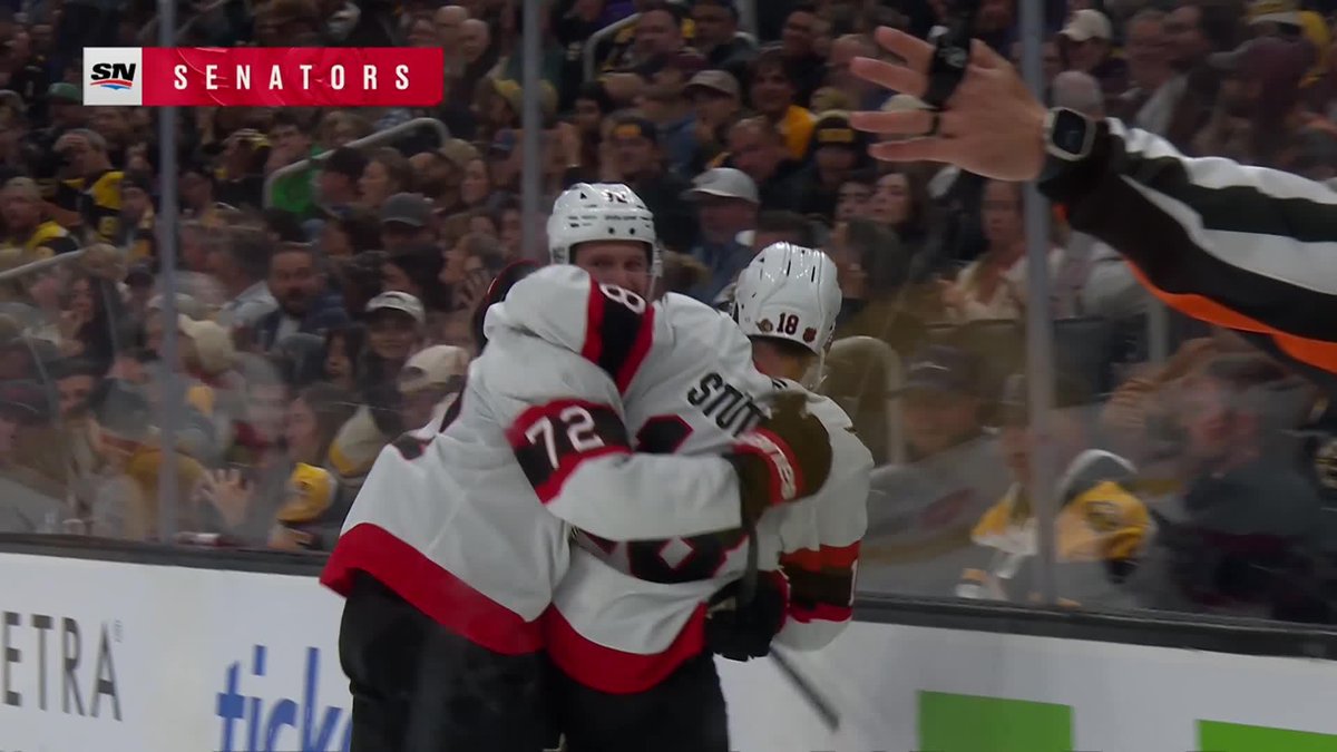 Hockey players in white jerseys with red and black trim (numbers 72 and 18 visible) celebrate on the ice in front of cheering fans, with an 'SN SENATORS' broadcast graphic.