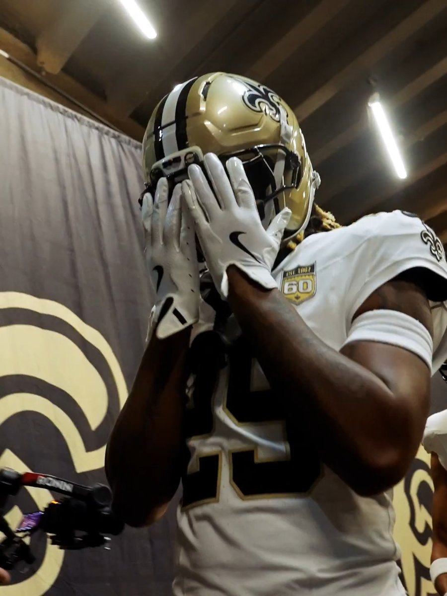 A football player wearing a New Orleans Saints helmet and a jersey with a "60" season anniversary patch covers his face with his white-gloved hands while standing in front of a Saints banner backdrop, likely during an ESPN interview or media session.