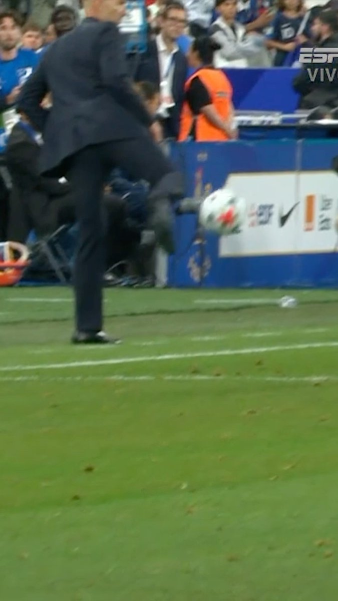 A man in a sharp suit—appearing to be Zinedine "Zizou" Zidane—is caught mid-action kicking a soccer ball on the pitch, showcasing the stylish footwork referenced in the caption. The ESPN broadcast watermark and sideline sponsor boards, including a visible Nike logo, frame this iconic sideline moment.