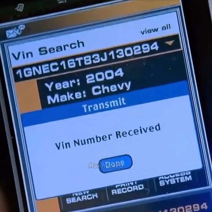 A close-up photo of a diagnostic device screen displaying a 'Vin Search' for vehicle '1GNEC16T83J130294', showing 'Year: 2004' and 'Make: Chevy', with 'Vin Number Received' in the main window.