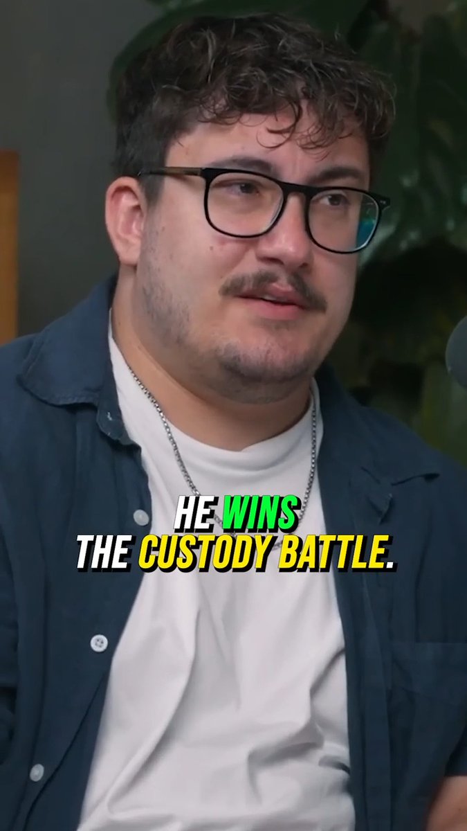 A young man with curly brown hair, glasses, a mustache, and a silver chain necklace is wearing a navy blue button-up shirt over a white t-shirt, with overlaid text reading "HE WINS THE CUSTODY BATTLE." The image appears to relate to the post about a Financial Audit father winning his custody lawsuit against the baby's mother.