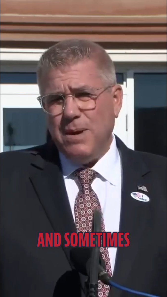 An older man in a suit and glasses speaks at a podium, with an 'I Voted' sticker on his lapel and red text overlaid reading 'AND SOMETIMES'.