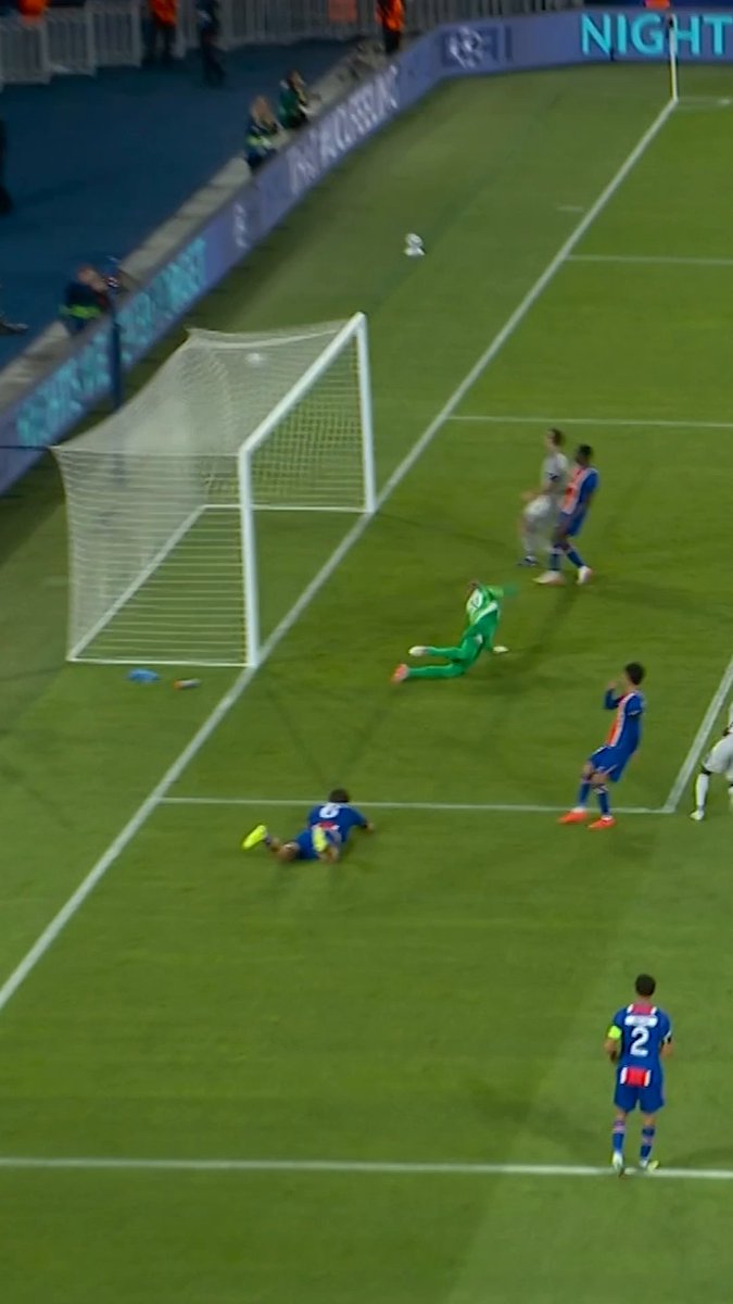 A soccer player in a green goalkeeper uniform dives but misses as the ball sails past into the net during a UEFA Champions League match, with a player wearing the number 2 visible in the foreground near advertising boards displaying "NIGHT." The image captures the dramatic moment of Camara's stunning goal in Paris, with players in blue and red kits reacting to the spectacular strike.