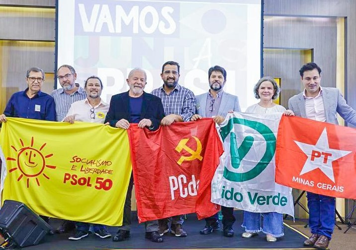 FeSpartani's tweet photo. @TrueLifeBetter The guy in black jacket is Lula (PT) president of Brazil. 

Can you tell me what is the symbol in the flag he is holding while smiling? 

Please study before calling someone "stupid" without knowing the context. https://t.co/bmwxhYXr4W