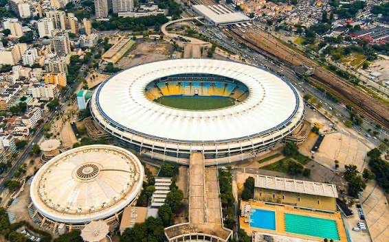 Aerial shot of the iconic Maracanã Stadium in Rio de Janeiro, featuring its distinctive circular white roof and surrounding sports complex, including the smaller arena and Olympic-sized pools. The post highlights the stadium as "Brazil's most sacred ground" and advocates for hosting the 2035 Rugby World Cup there, citing its historic sporting legacy.