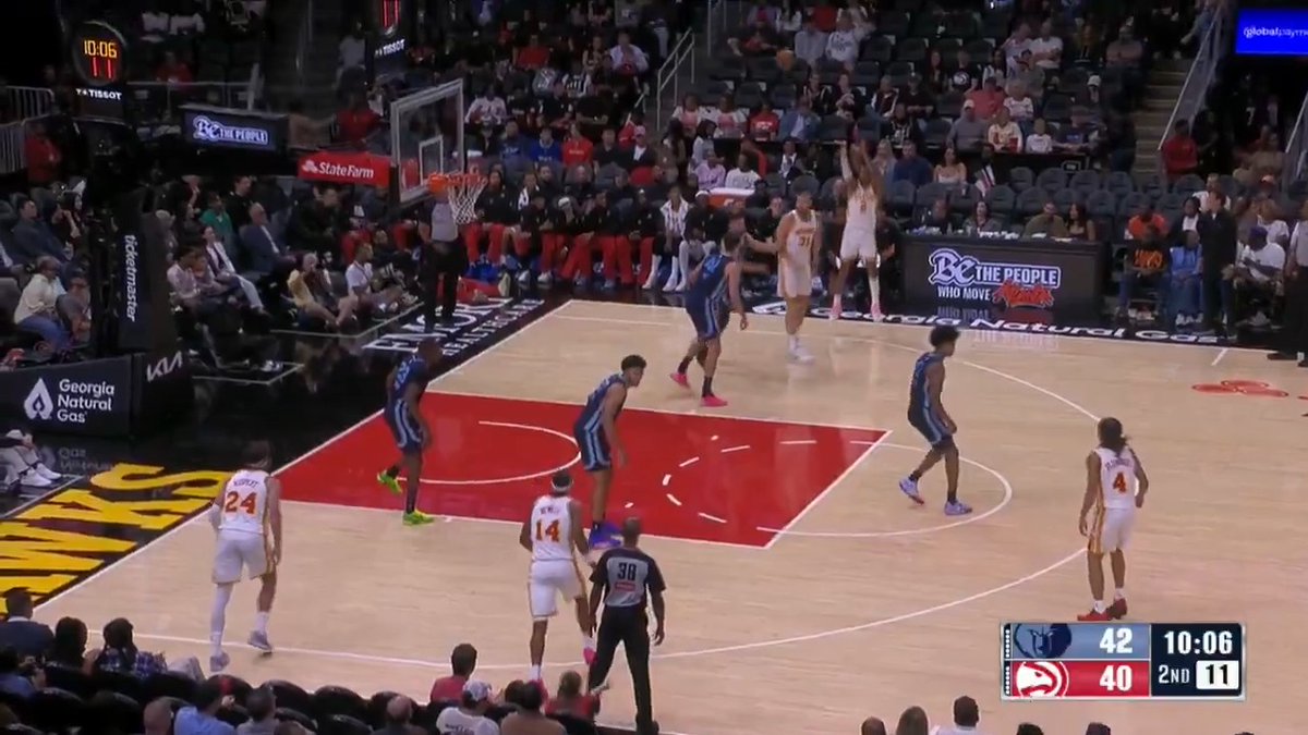 A basketball game scene showing a player taking a jump shot while defenders converge, with the scoreboard displaying Memphis Grizzlies 42 and Atlanta Hawks 40 at 10:06 in the 2nd quarter with 11 seconds on the shot clock. The image captures Aaron Wiggins' made three-pointer, the "first triple" referenced in the caption, extending the Grizzlies' lead over the Hawks.