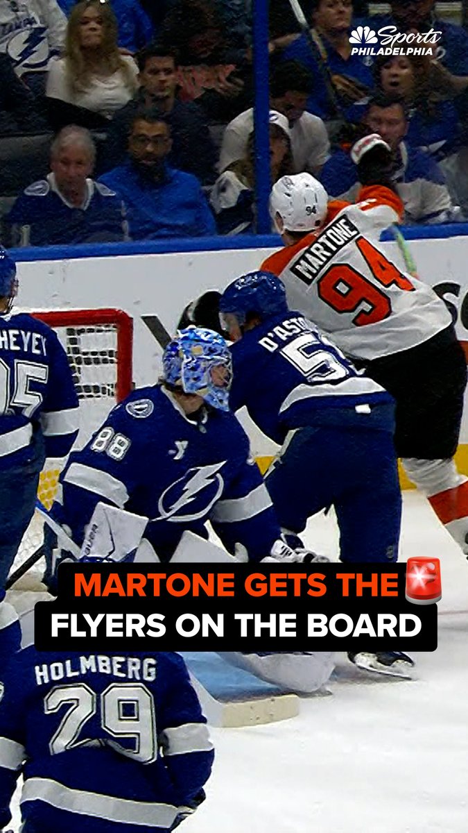 Flyers rookie Porter Martone (#94) celebrates near the Tampa Bay Lightning net after scoring his first career NHL goal, with Lightning goaltender Jonas Johansson (#88) and defenseman Darren Raddysh (also visible, #5 D'Astous) looking on. The image, branded by NBC Sports Philadelphia, visually corresponds to the post's caption announcing that "Martone gets the Flyers on the board" with an alert banner emphasizing his milestone goal.
