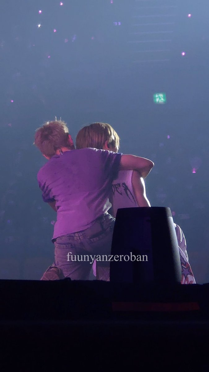 Two people embracing on stage at a concert with purple lighting and confetti in the air, watermarked "fuunyanzeroban".