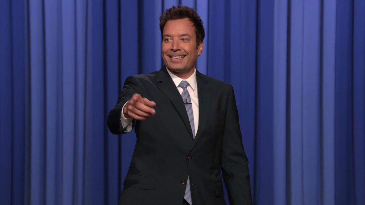 Jimmy Fallon points at the camera and laughs on the set of "The Tonight Show," with blue curtains forming the backdrop. The post references the show, joking about the moment Vivek Ramaswamy's campaign faltered during an awkward attempt to lift a child at a Trump rally.