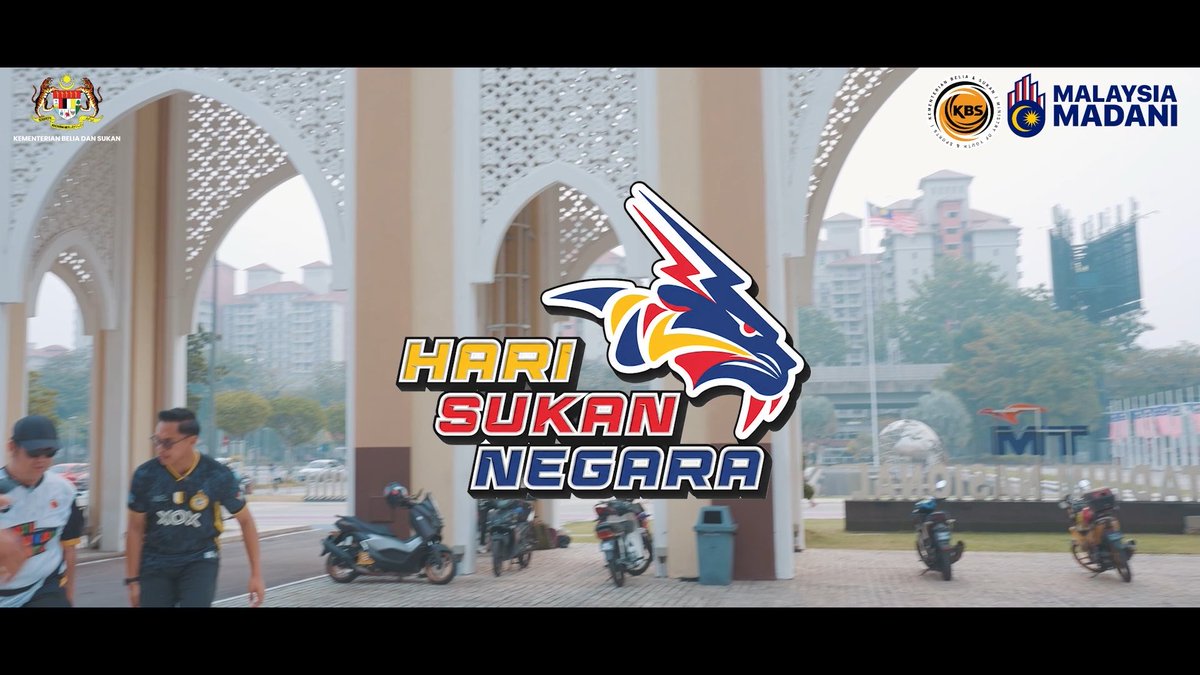A promotional graphic for 'HARI SUKAN NEGARA' (National Sports Day) featuring a colorful tiger mascot logo, with the Ministry of Youth and Sports (Kementerian Belia dan Sukan) crest, KBS logo, and 'MALAYSIA MADANI' branding displayed over a background of arched architecture and motorcyclists.