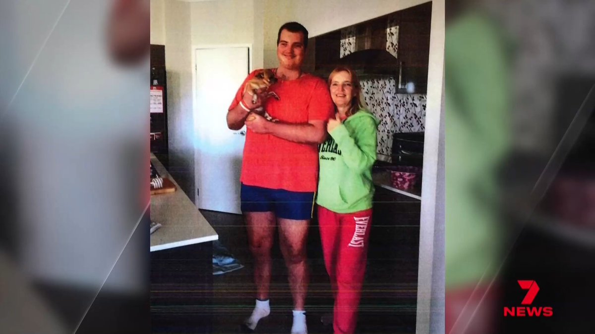 A Channel 7 News screenshot showing a tall man in a red shirt holding a small puppy, standing next to a woman in a green hoodie and red pants in a kitchen setting.
