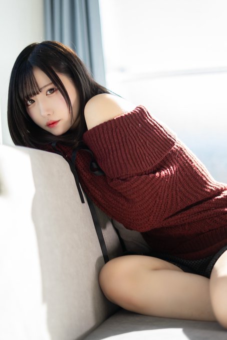 The image shows a young woman with long dark hair, wearing an off-shoulder burgundy knit sweater, posing softly on a couch in a sunlit room. The caption "Good work today too ˙⋆✮" complements the image with a sweet, encouraging tone, as if praising the subject for her hard work.
