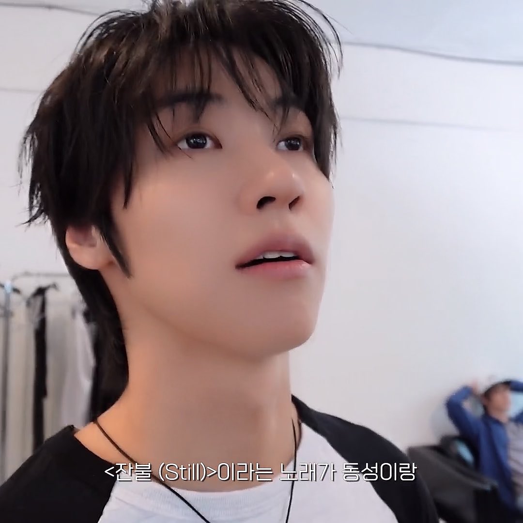 A close-up of a young man with dark, messy hair speaking, with Korean subtitles reading '<잠볼 (Still)>이라는 노래가 통성이랑'.
