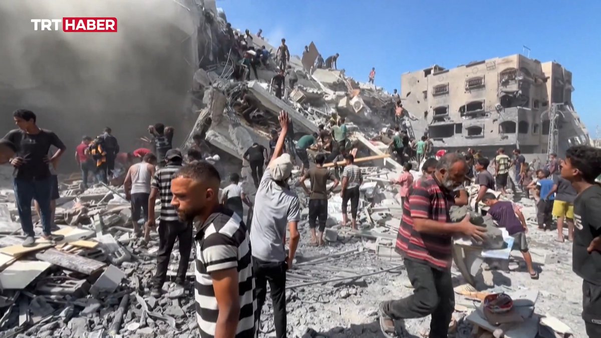 The image shows people searching through the rubble of destroyed buildings amid rising dust, with the "TRT HABER" logo visible in the corner. It depicts the aftermath of airstrikes in Gaza, accompanying a post announcing TRT's special broadcasts commemorating the third anniversary of the ongoing humanitarian crisis there.