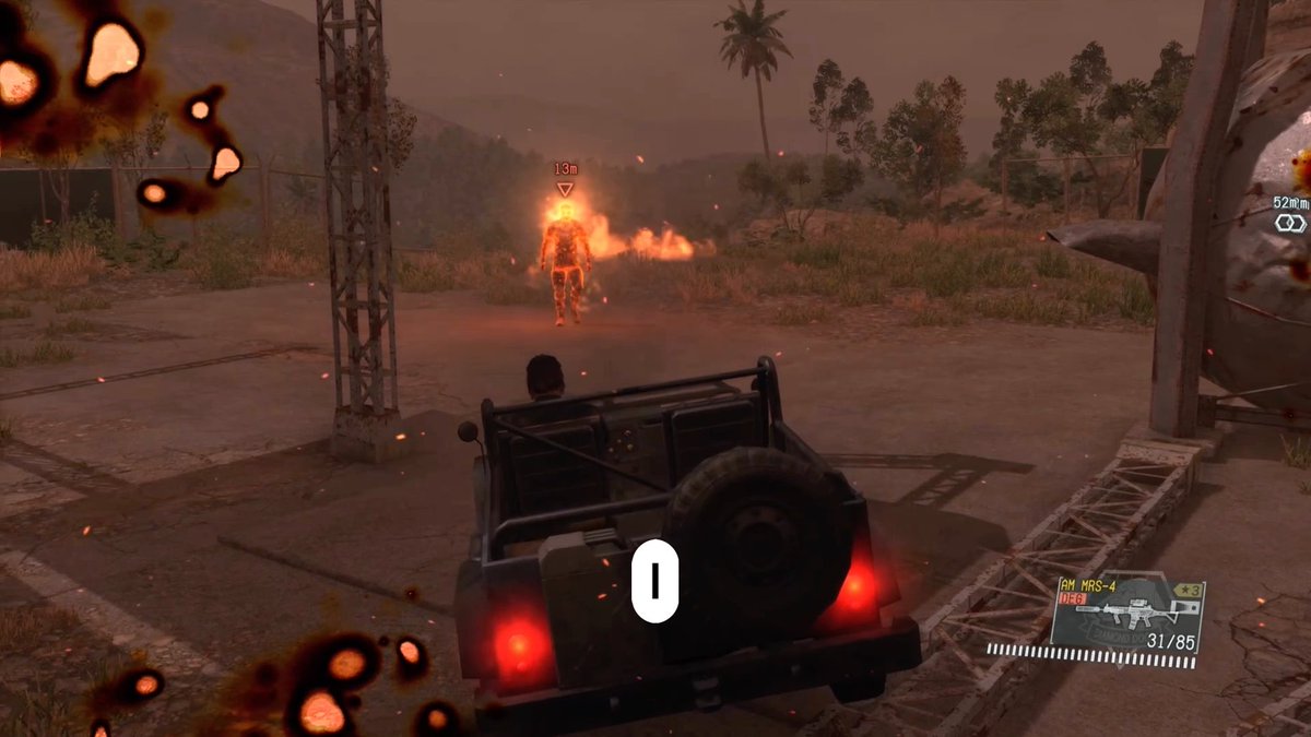 A third-person video game screenshot showing a player in a jeep driving through a dusty, war-torn environment with palm trees, encountering a flaming enemy figure marked at 13 meters distance, with the AM MRS-4 rifle weapon displayed in the HUD.