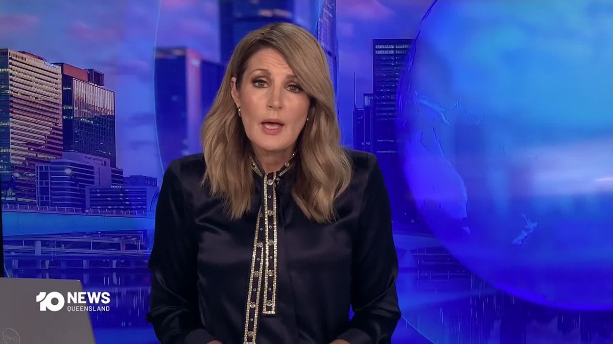 A female news anchor presents from the 10 News Queensland studio, wearing a black blouse with gold trim, set against a purple-tinted cityscape backdrop.