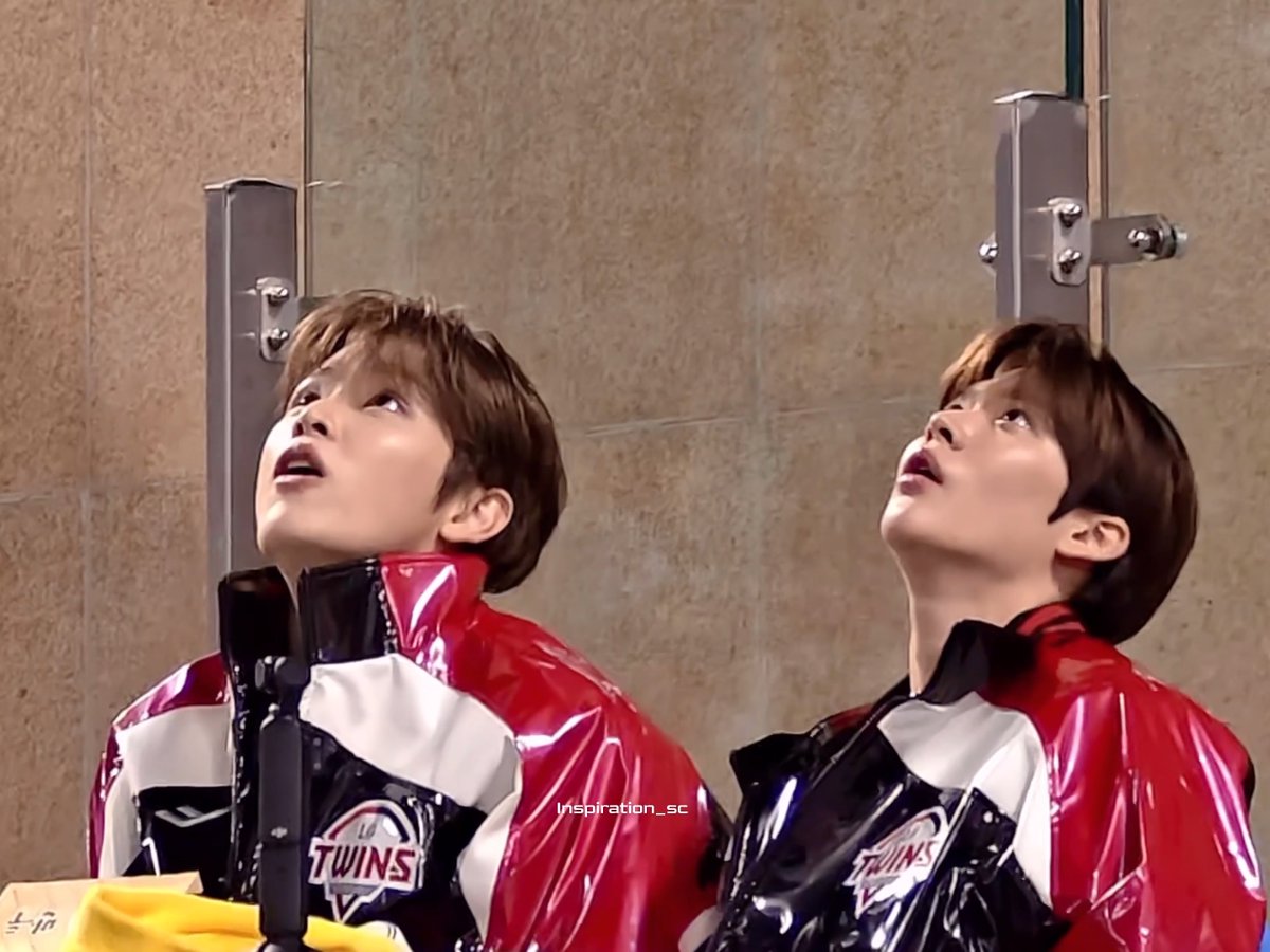 Two young men in matching red and black 'Twins' jackets looking upward with surprised expressions against a stone wall, with 'inspiration_sc' watermark visible.