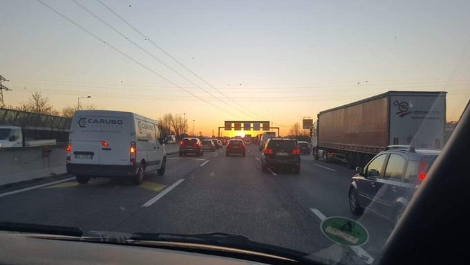 A dashboard view of congested highway traffic during sunset, featuring a 'CASUSO' van and a large logistics truck in the lanes ahead.