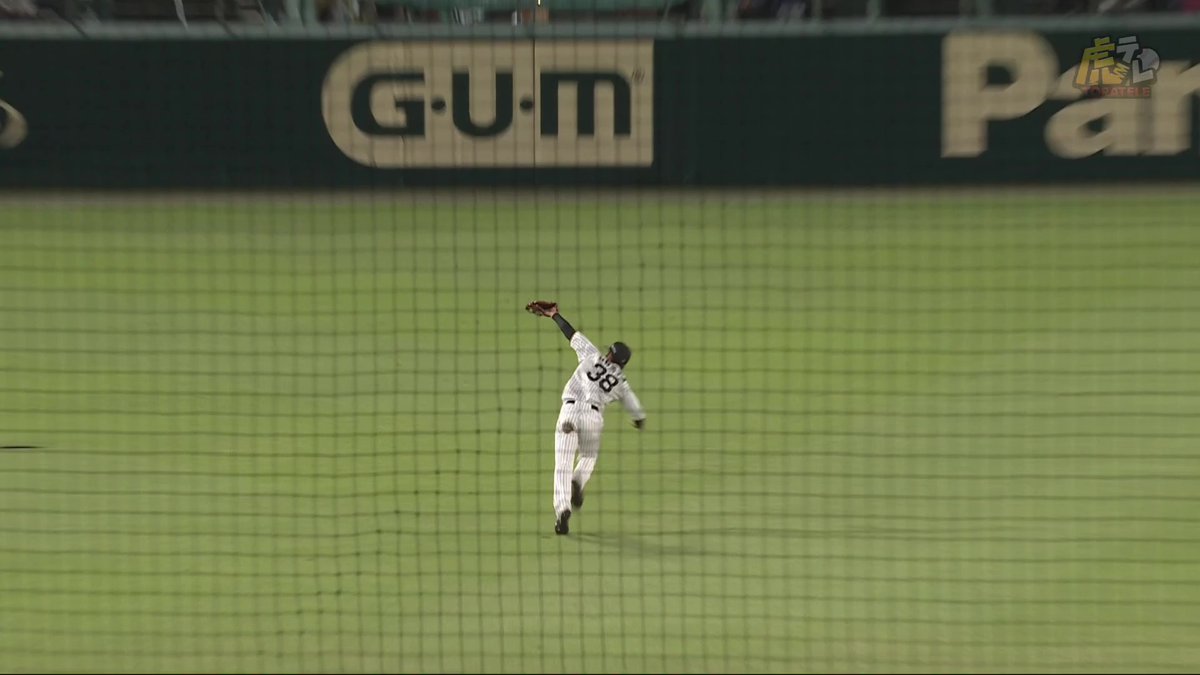 A baseball player in a pinstriped uniform with number 8 makes a leaping catch in the outfield, with "GUM" and "Panasonic" advertisements visible on the outfield wall behind him, exemplifying the spectacular outfield grab referenced in the caption about Obata's defensive skill.