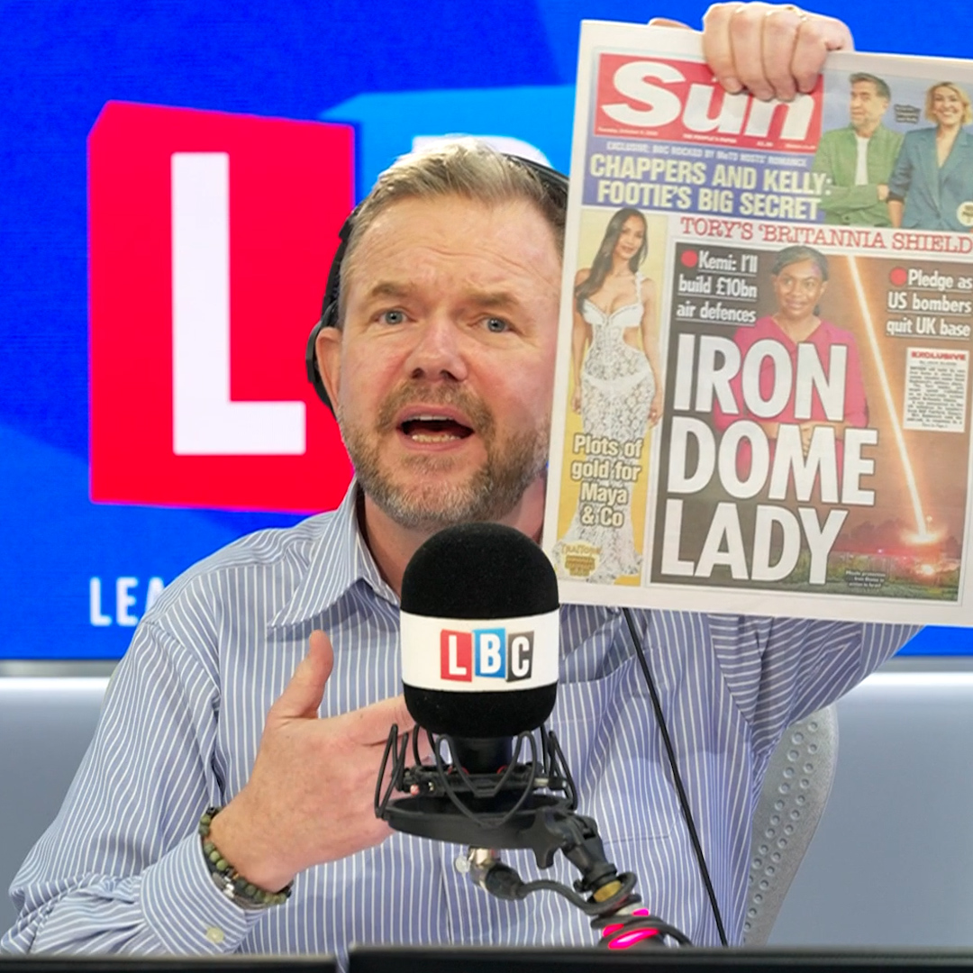 James O'Brien holds up The Sun newspaper featuring a front-page headline about Kemi Badenoch's "IRON DOME LADY" branding and "TORY'S 'BRITANNIA SHIELD'" defense policy during his LBC radio show, visually illustrating his critique of her vague policy announcement.