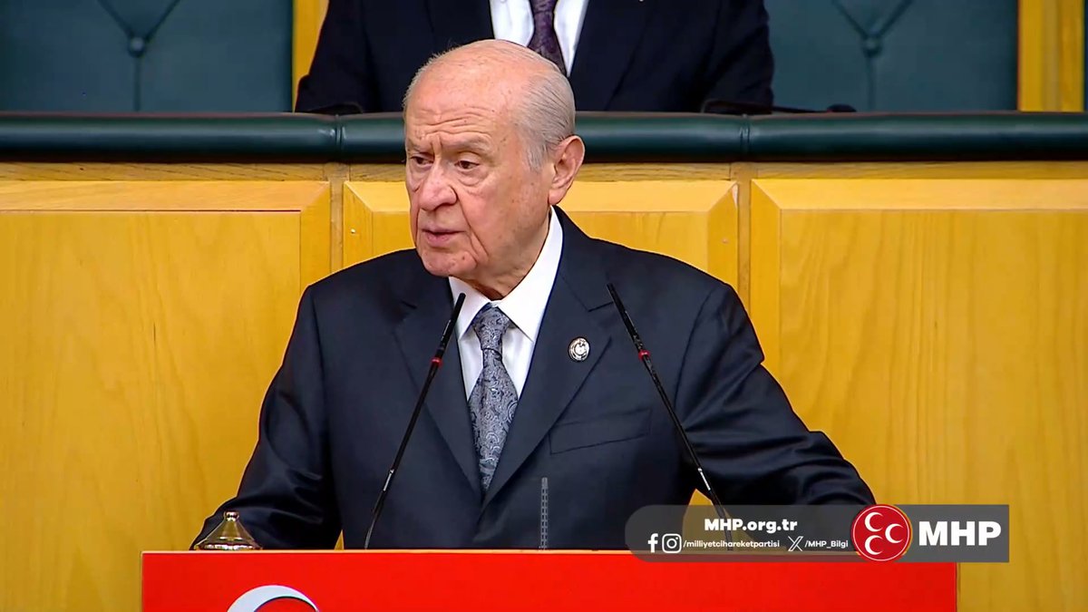 An elderly man in a dark suit and patterned tie speaks at a podium adorned with the MHP logo, with the watermark "MHP.org.tr" and the party's official social media handles visible, aligning with the message presenting the Nationalist Movement Party (MHP) as a historically rooted political force.