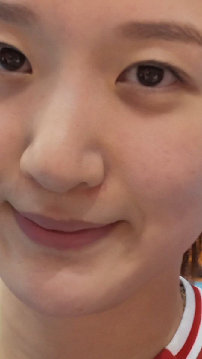A close-up selfie of a young woman's face, focusing on her eyes and lips, wearing a red and white striped top.