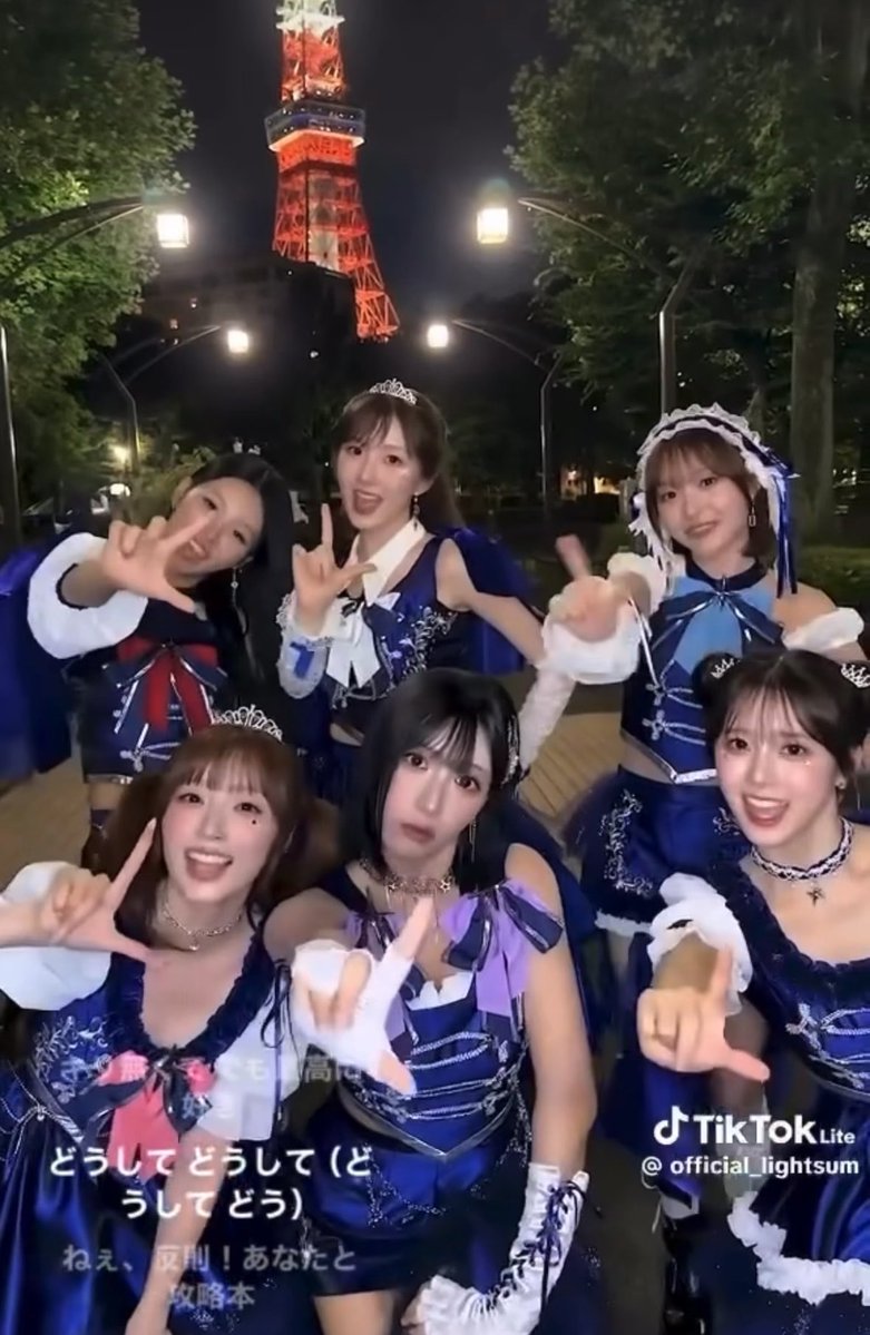 A TikTok screenshot of six young women in matching blue and white idol costumes posing with peace signs in front of Sapporo Tower at night, with Japanese subtitles and the handle '@official_lightsum'.