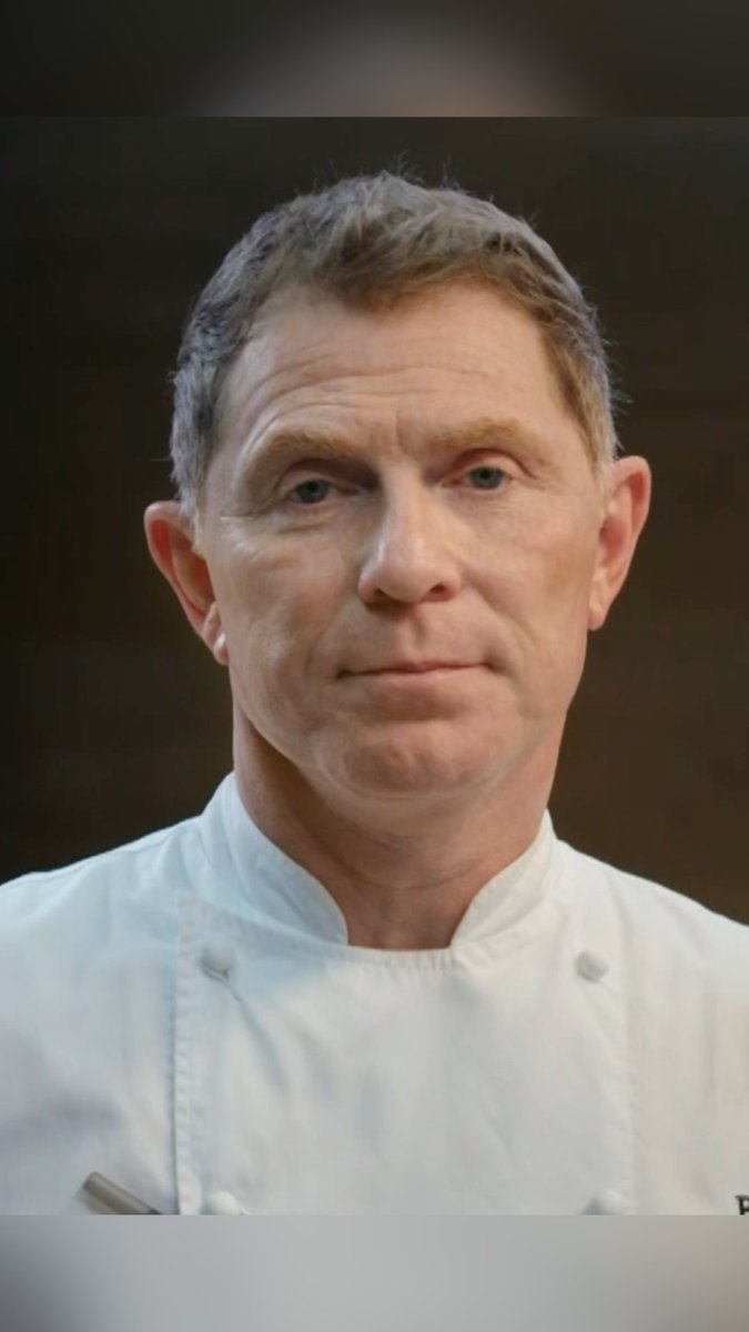 A portrait of a middle-aged man with short brown hair wearing a white chef's coat against a dark background.