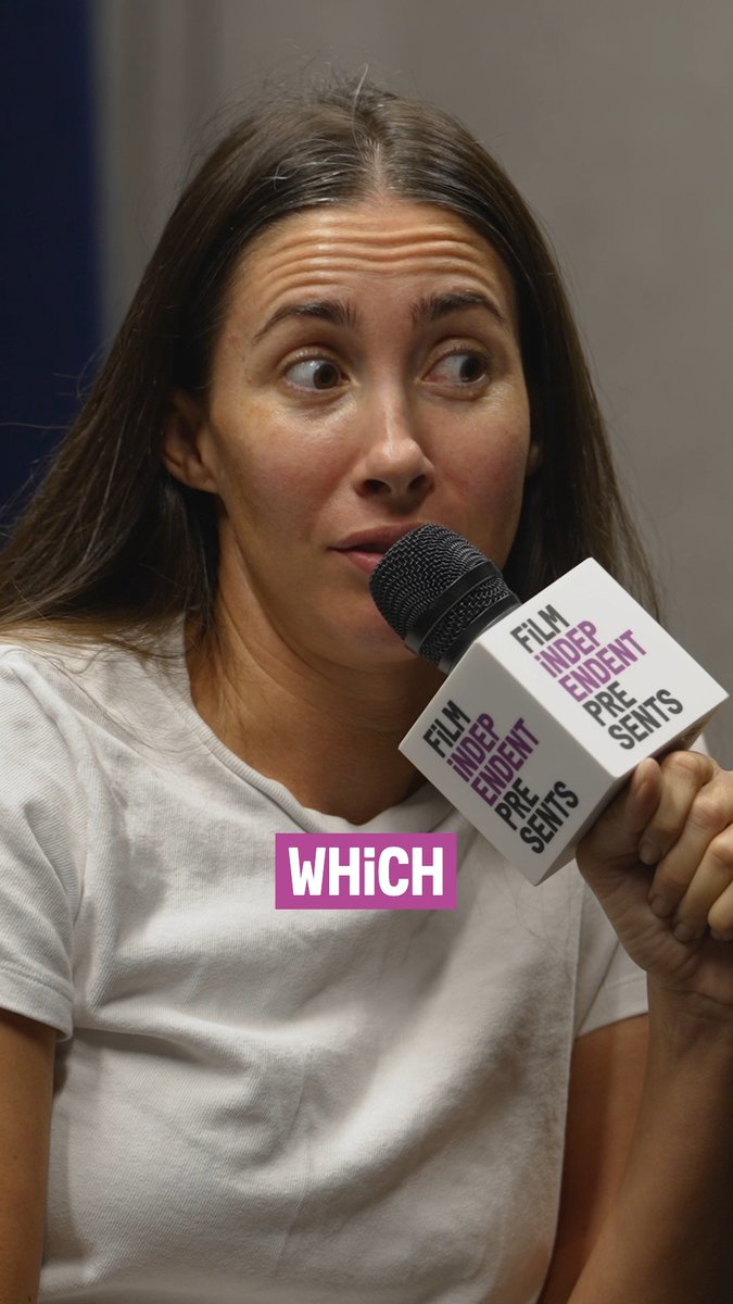 A woman with long brown hair speaks into a microphone labeled 'Film Independent Presents' at what appears to be a press event, with 'WHICH' displayed below.
