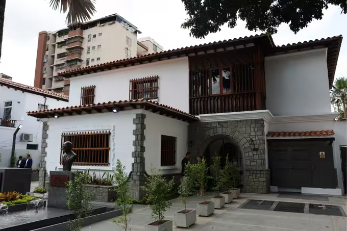 A colonial-style white building with stone accents and red tile roofing stands in Caracas, serving as the newly inaugurated José Antonio Abreu University of Music, where President Rodríguez likely attended the opening ceremony amid a modern urban backdrop.
