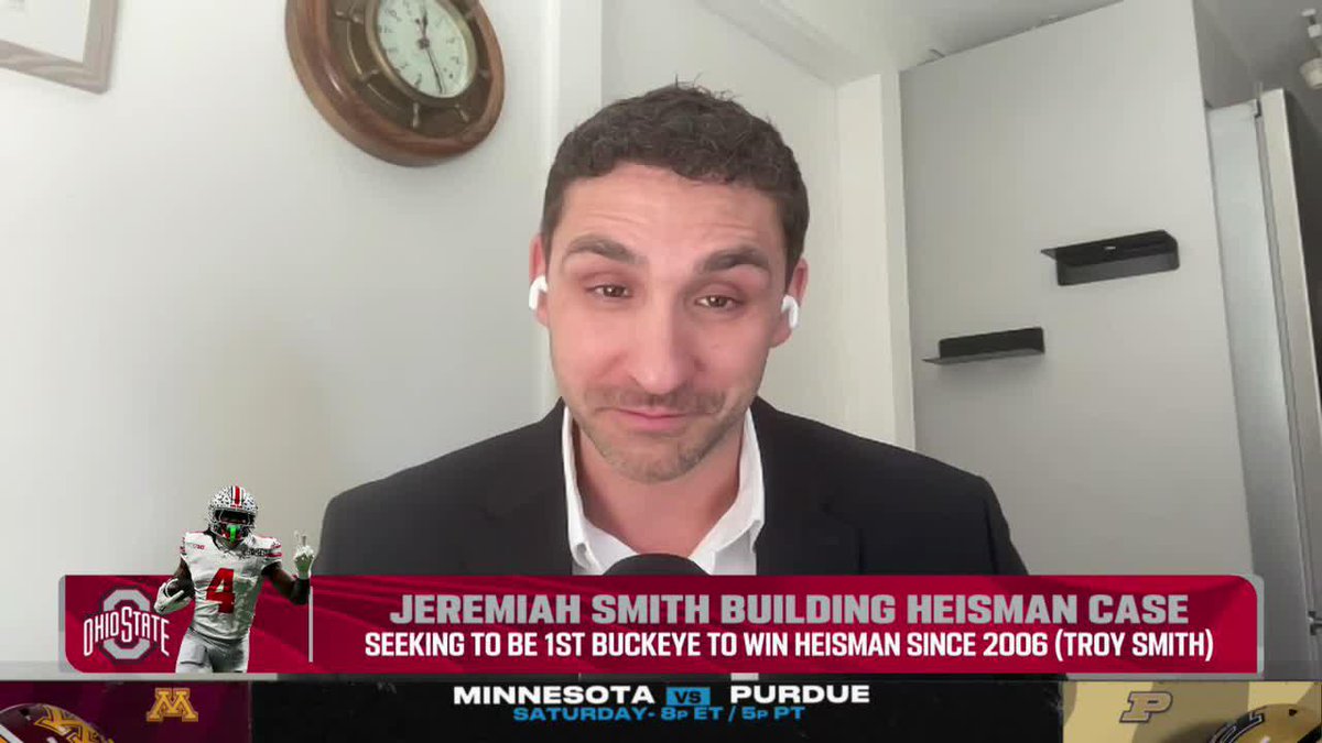 A man wearing earbuds and a dark blazer appears on a Big Ten Network broadcast discussing Jeremiah Smith's Heisman case, with on-screen graphics reading "JEREMIAH SMITH BUILDING HEISMAN CASE - SEEKING TO BE 1ST BUCKEYE TO WIN HEISMAN SINCE 2006 (TROY SMITH)" alongside his Ohio State #4 photo, and a ticker below promoting Minnesota vs Purdue on Saturday at 8PM ET. The caption highlights Smith's record-setting season as the analyst speaks during what appears to be the B1G Today show.