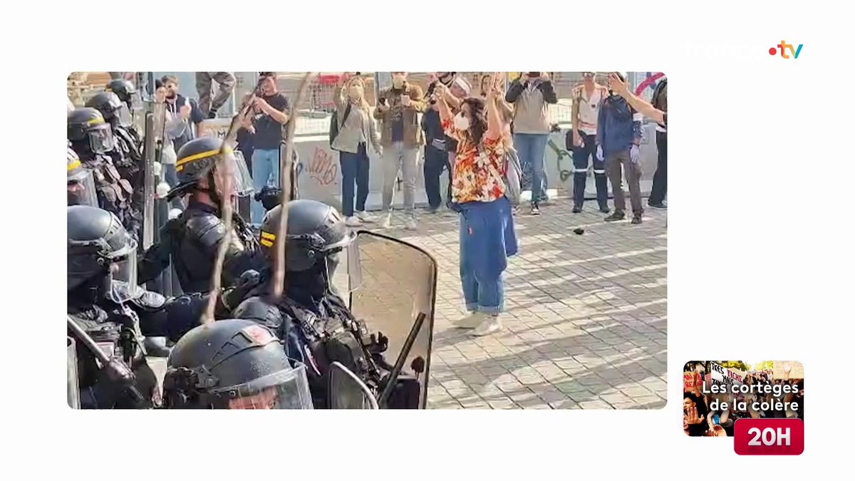 A screenshot from a news broadcast showing riot police in helmets facing off against protesters with raised hands, labeled "Les cortèges de la colère" and "20H".