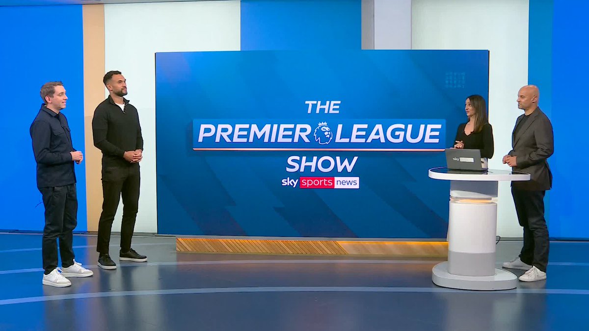 Four people are pictured on a TV studio set in front of a blue screen displaying "THE PREMIER LEAGUE SHOW" along with the Sky Sports News logo. The two men on the left appear to be preparing for the "quickfire questions" segment with Steven Caulker, while two hosts stand on the right beside a small podium with a Sky Sports laptop.