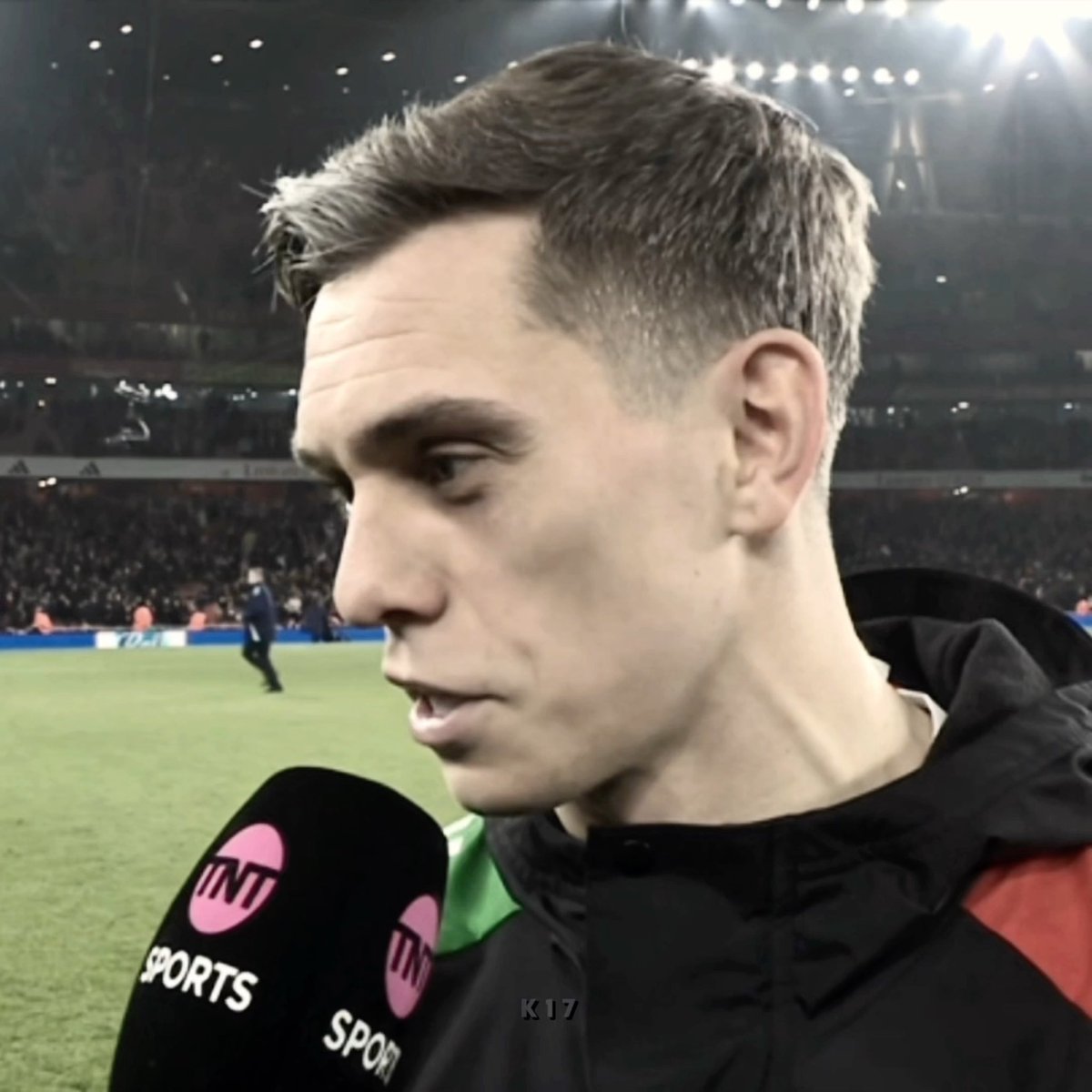 A close-up profile shot of a young male athlete being interviewed on a soccer field by a reporter holding a microphone with the 'TNT SPORTS' logo.