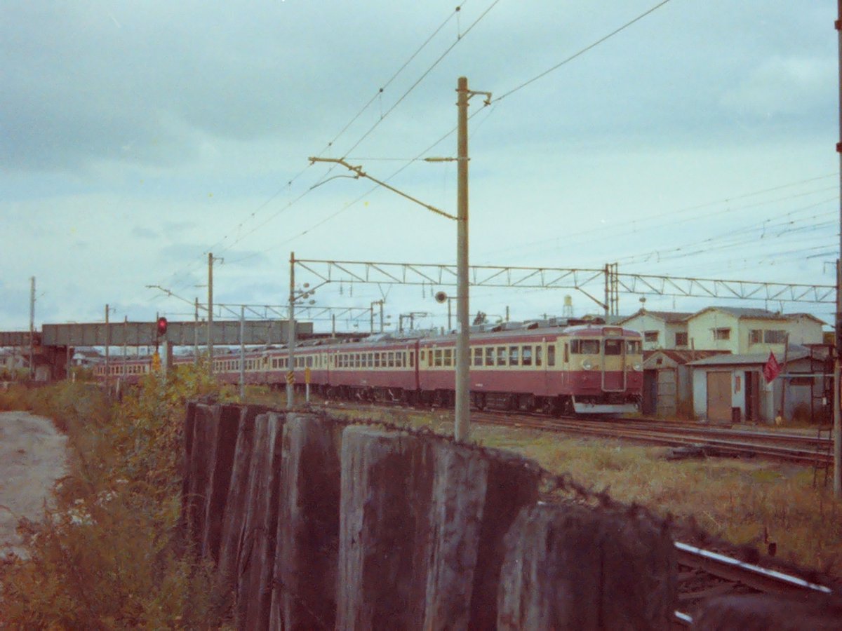 maxyupiro's tweet photo. 80年頃撮影。仙台運転所(現・仙台車両ベース)を出ていく455系です。
もう46年前の写真ですが、右側の労組の旗がある小屋、その向こうに見えるクリーム色の一軒家は現存しています。 https://t.co/y3pinJCMtS