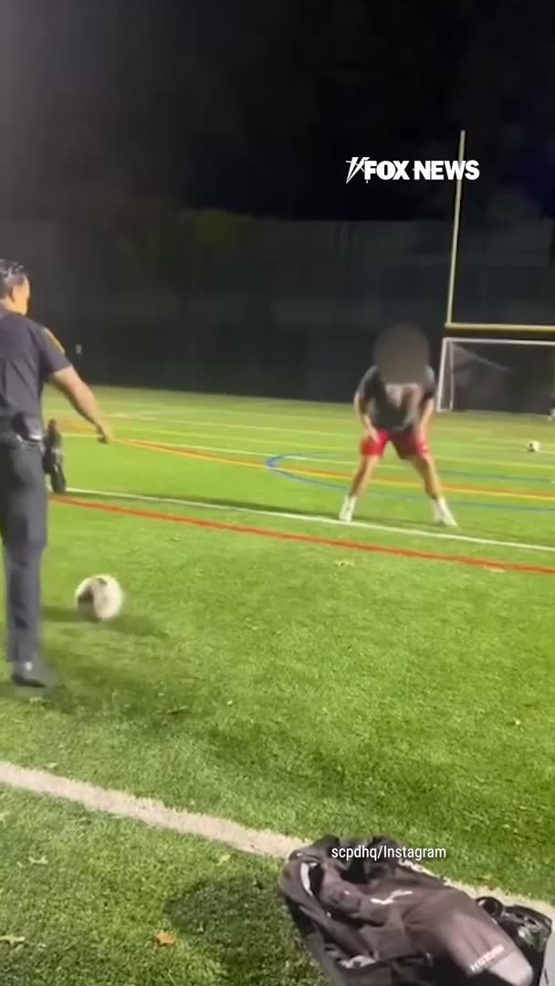 A police officer points on a nighttime soccer field toward a kid in red shorts, with the "FOX NEWS" logo displayed and a credit to "scpdhq/Instagram" visible, illustrating the moment cops approached the kids' game before joining in rather than shutting it down.