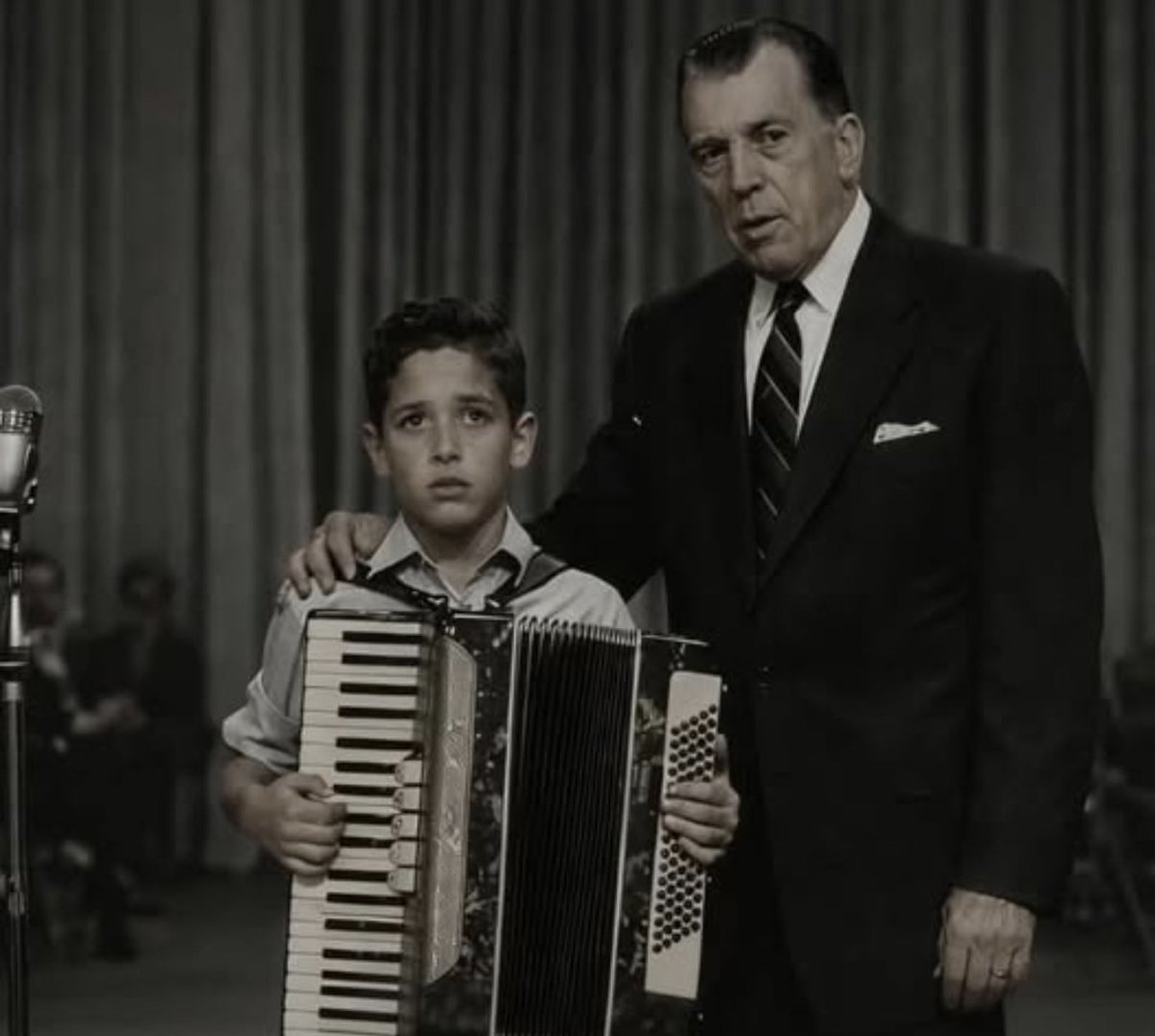 Visionaryvoid's tweet photo. The boy was only 11 years old when he stepped onto the stage of The Ed Sullivan Show, his old accordion almost as big as he was. His grandfather had brought it from Italy, and his grandmother had taught him the piece he was about to play. But as he stood beneath the bright studio lights, a few people in the audience began to laugh at him and his old-fashioned instrument. His face turned red, his fingers trembled, and for a moment, he looked as though he might cry. He had practiced for months, and now, before playing a single note, he felt completely humiliated.

Ed Sullivan noticed. Instead of letting the moment continue, he walked onto the stage and placed a gentle hand on the boy’s shoulder. The laughter stopped. Sullivan looked at the audience and calmly told them that this was an 11-year-old child standing before hundreds of people, brave enough to share something he loved. He asked them to give the boy the respect they would want if they were standing in his place. Then he turned to the trembling child and asked what he was going to play. “Tarantella,” the boy quietly answered. Sullivan smiled and said, “Beautiful choice. Whenever you’re ready. Take your time.”

The boy took a deep breath, looked down at his accordion, and began to play. What followed was extraordinary. His fingers moved quickly and confidently across the keys, and the little accordion filled the studio with bright, joyful music. The audience that had laughed moments earlier became completely silent, listening with respect. When the final note ended, the room erupted in genuine applause. The boy stood taller, his tears replaced by a smile, while Sullivan walked over and shook his hand with genuine respect.

Years later, the boy remembered that moment not simply because millions had watched him perform, but because one man had chosen to stand beside him when he was vulnerable. Sullivan could have allowed the moment to pass, but instead, he made a frightened child feel seen and valued. Sometimes, kindness doesn’t require a grand gesture. Sometimes, all it takes is one person stepping forward and saying, in effect, “You matter. Take your time. We’re listening.