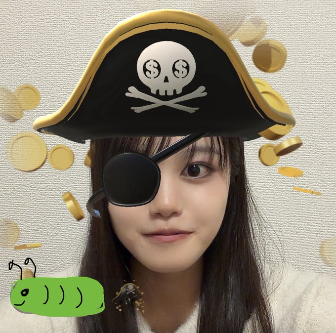 A selfie of a young woman with a digital pirate hat filter featuring a skull with dollar sign eyes, coins raining down, and a green caterpillar sticker graphic in the corner.