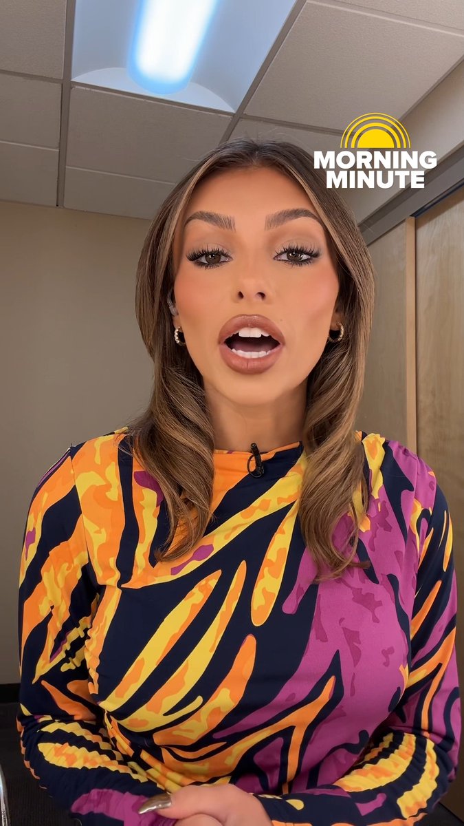 A news anchor wearing a vibrant, multicolored zebra-striped blouse, appearing on screen with a 'MORNING MINUTE' graphic in the top right.