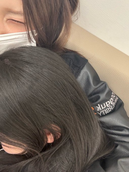 A close-up selfie shows Jiwoo, wearing a black "beauty LIBERTY" jacket, resting her head against someone wearing a white mask, with her long dark hair cascading down. The intimate moment captures the warmth of the embrace she mentioned, despite his initial reluctance due to her cold.