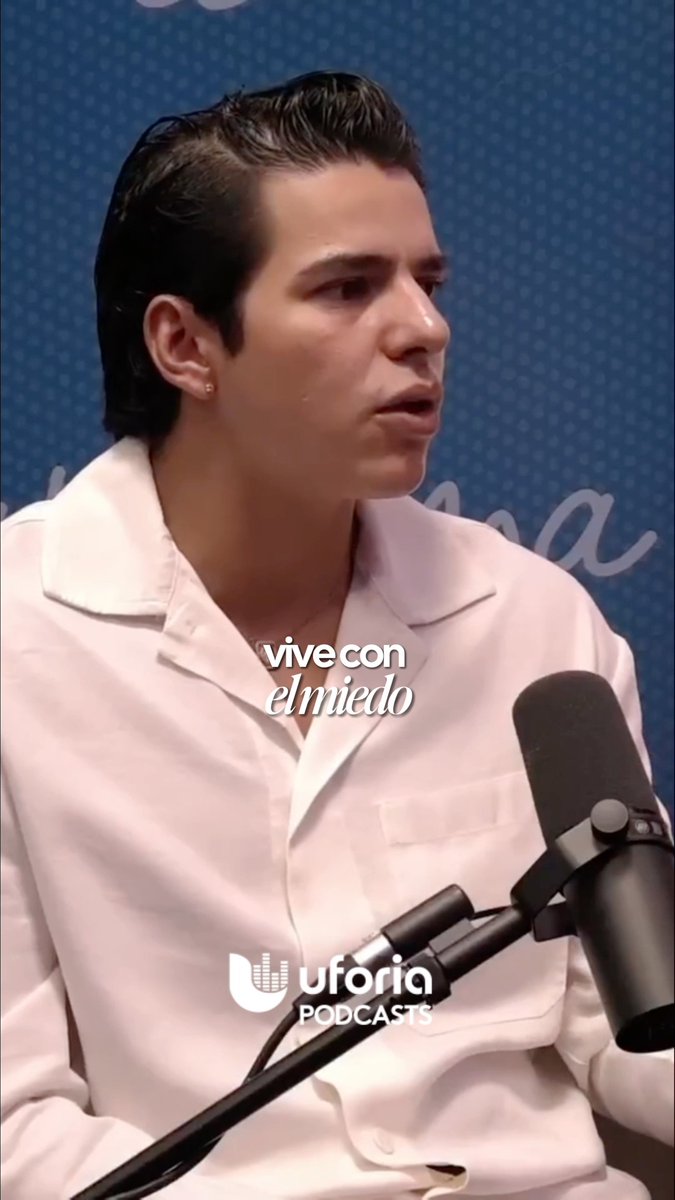 A young man in a white shirt speaks into a microphone during a podcast, with the caption 'vive con el miedo' and the 'uforia PODCASTS' logo visible.