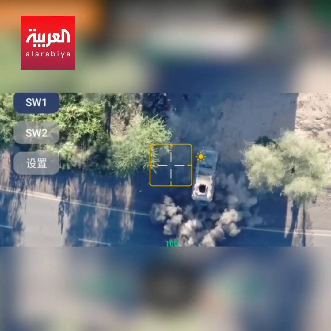 The image shows aerial drone footage from Al Arabiya (العربية) with an SW1 camera designation, displaying a yellow targeting reticle locked onto a vehicle on a road surrounded by trees, with dust plumes visible from an apparent strike. This corresponds to the reported Yemeni Armed Forces drone operation targeting Houthi militia positions west of Taiz.