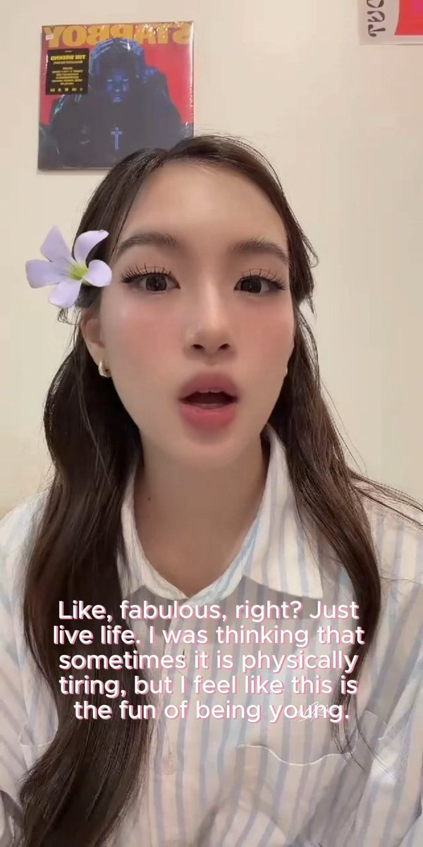 A young woman with a purple flower hair accessory speaking, with subtitles reading: 'Like, fabulous, right? Just live life. I was thinking that sometimes it is physically tiring, but I feel like this is the fun of being young.'