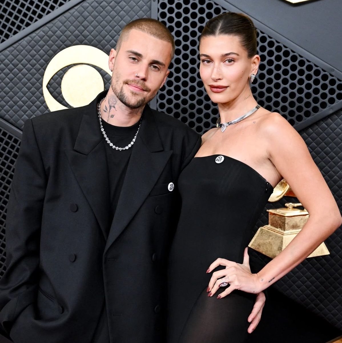 biebrupdates's tweet photo. No Grammy de 2026, Justin e Hailey Bieber apareceram usando o broche “ICE OUT”.

O símbolo estava sendo utilizado naquele momento como protesto contra as ações da ICE (Immigration and Customs Enforcement) e contra as políticas de imigração do governo Trump. A imprensa descreveu explicitamente os broches usados pelos artistas como uma manifestação contra as políticas de imigração de Trump.