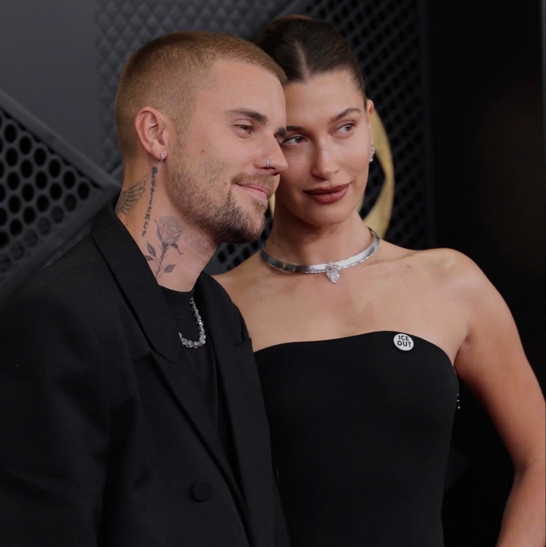 biebrupdates's tweet photo. No Grammy de 2026, Justin e Hailey Bieber apareceram usando o broche “ICE OUT”.

O símbolo estava sendo utilizado naquele momento como protesto contra as ações da ICE (Immigration and Customs Enforcement) e contra as políticas de imigração do governo Trump. A imprensa descreveu explicitamente os broches usados pelos artistas como uma manifestação contra as políticas de imigração de Trump.