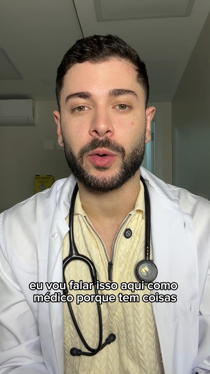 A man with a beard wearing a white lab coat and stethoscope speaks directly to the camera in what appears to be a medical office. The Portuguese subtitle reads "eu vou falar isso aqui como médico porque tem coisas" (I will say this here as a doctor because there are things), indicating he is a medical professional addressing the serious topics of femicide and violence against vulnerable people mentioned in the post.